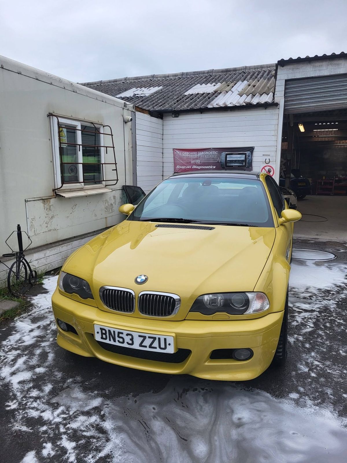 The same coupe finished, its bright yellow paintwork gleaming after the wash